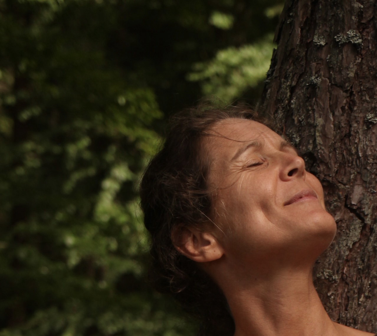 Christina lehnt mit geschlossenen Augen an einem Baum